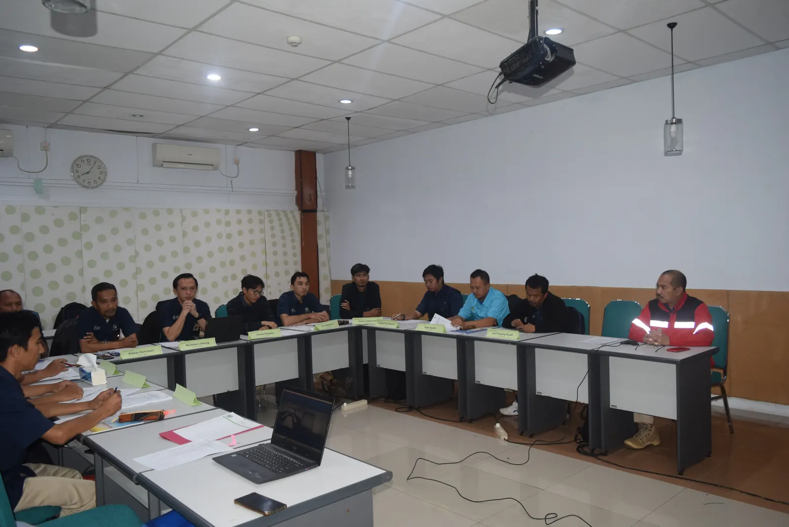 Peserta pelatihan K3 dengan name tag duduk di meja U-shape mengikuti presentasi di ruang kelas