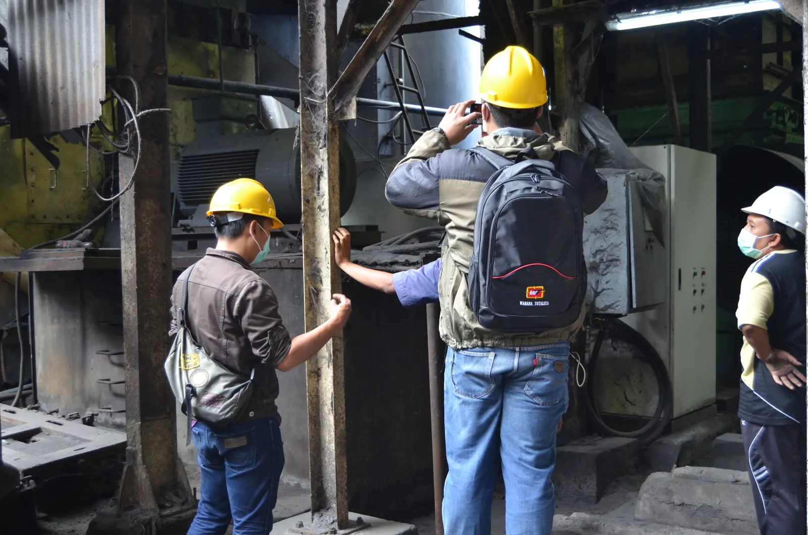 Auditor K3 PT Wahana Totalita mendokumentasikan kondisi mesin di area pabrik menggunakan helm kuning