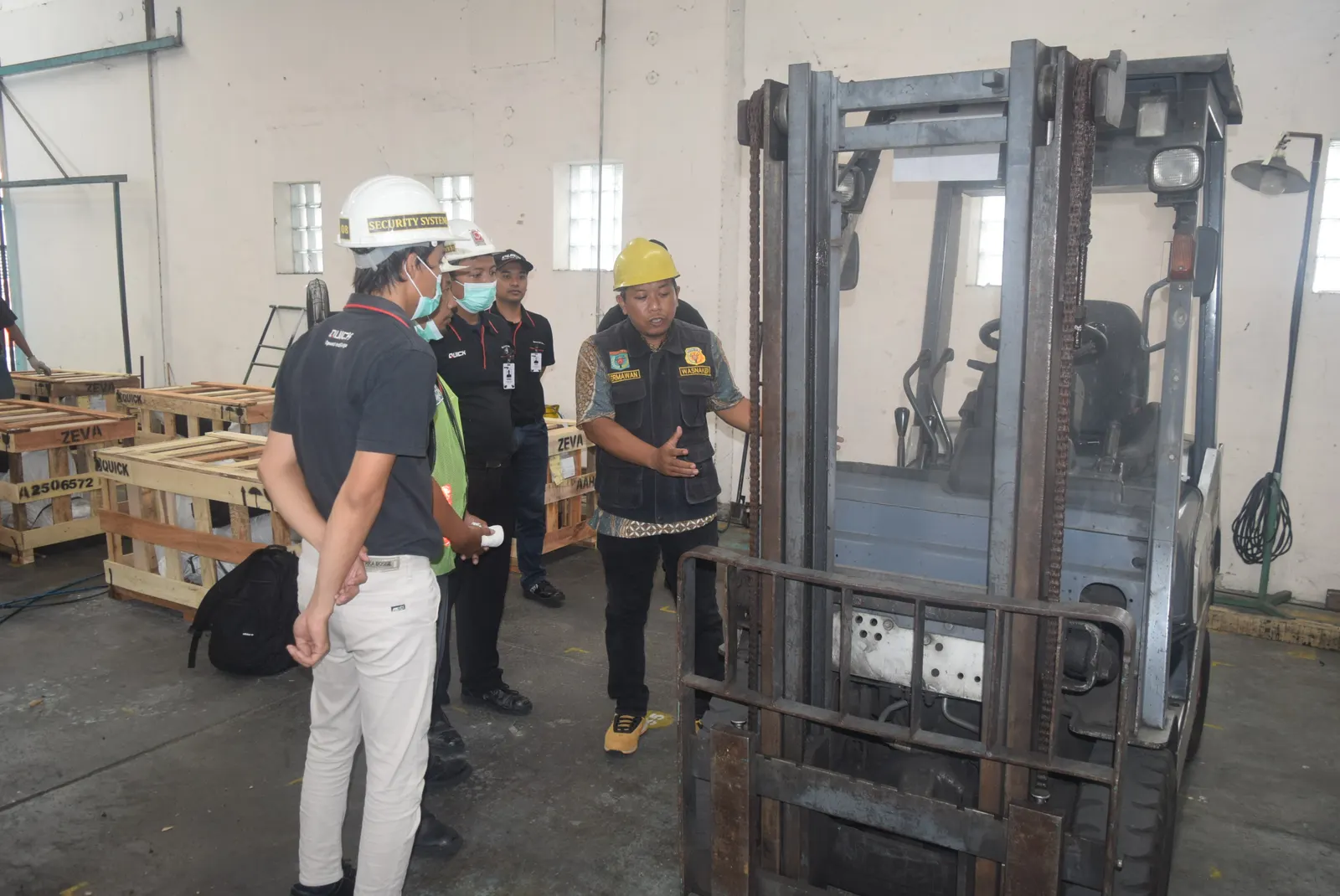 Inspeksi K3 forklift di area gudang pabrik oleh tim auditor berhelm dan berseragam safety