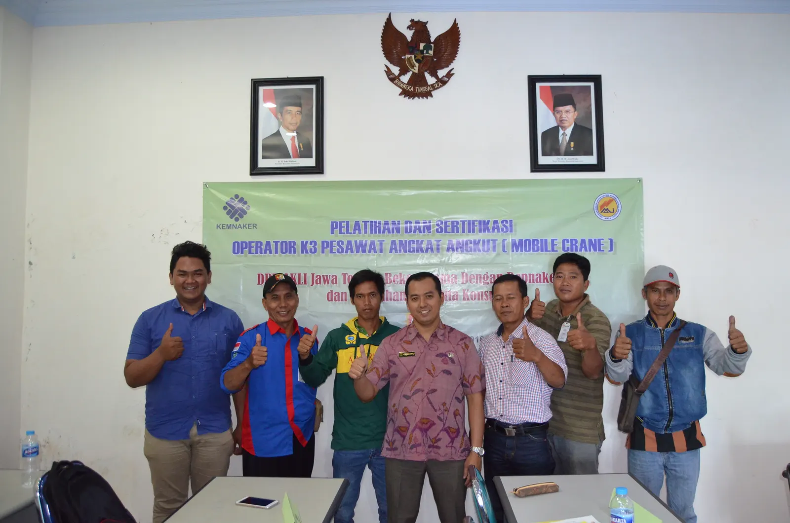 Peserta pelatihan dan sertifikasi operator K3 pesawat angkat angkut mobile crane berfoto dengan spanduk Kemnaker