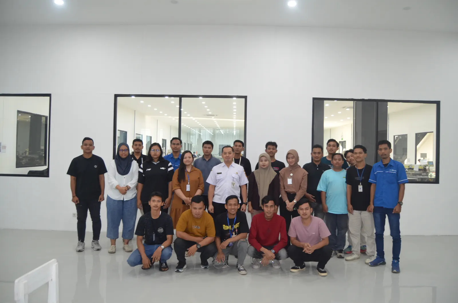 Foto bersama peserta pelatihan dengan pejabat pemerintah di ruang kantor modern dengan jendela kaca besar