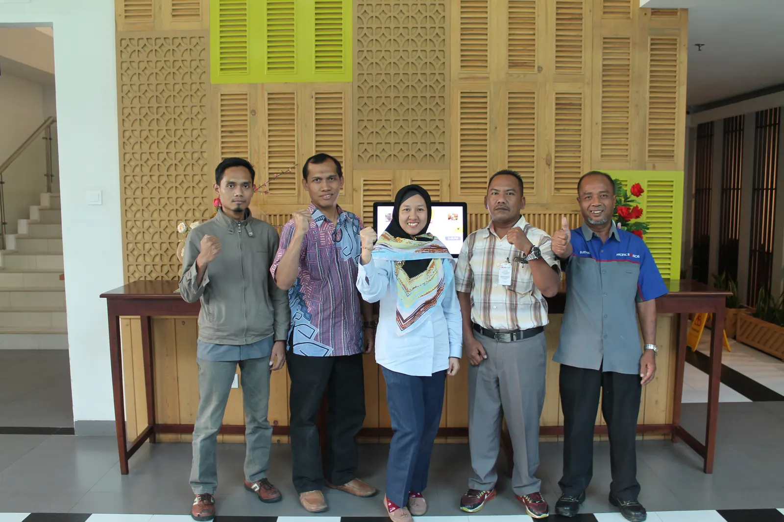 Tim peserta pelatihan K3 berfoto di lobi hotel dengan dekorasi panel kayu ukiran tradisional